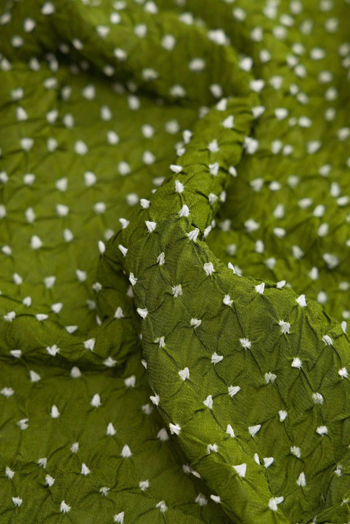 Close up of Mehandi Green Dual Tone Bandhani Silk Saree with Bandhani Print on the body and Zari Border.  displaying folds
