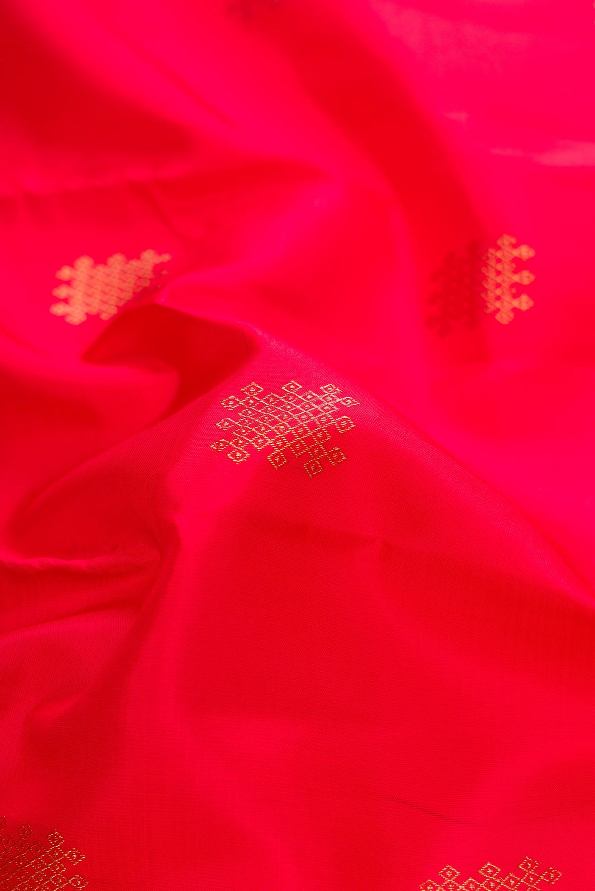 Close up of Red Dual Tone Kanchipuram Silk Saree with Zari Butta on the body and Without Border.  displaying folds