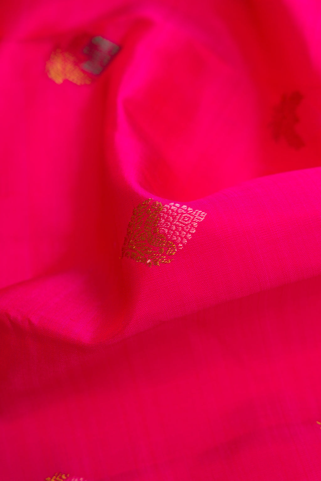 Close up of Pure Silk Pure Zari Pink Kanjivaram Saree with Zari And Thread Butta on the body and Plain Border.  displaying folds