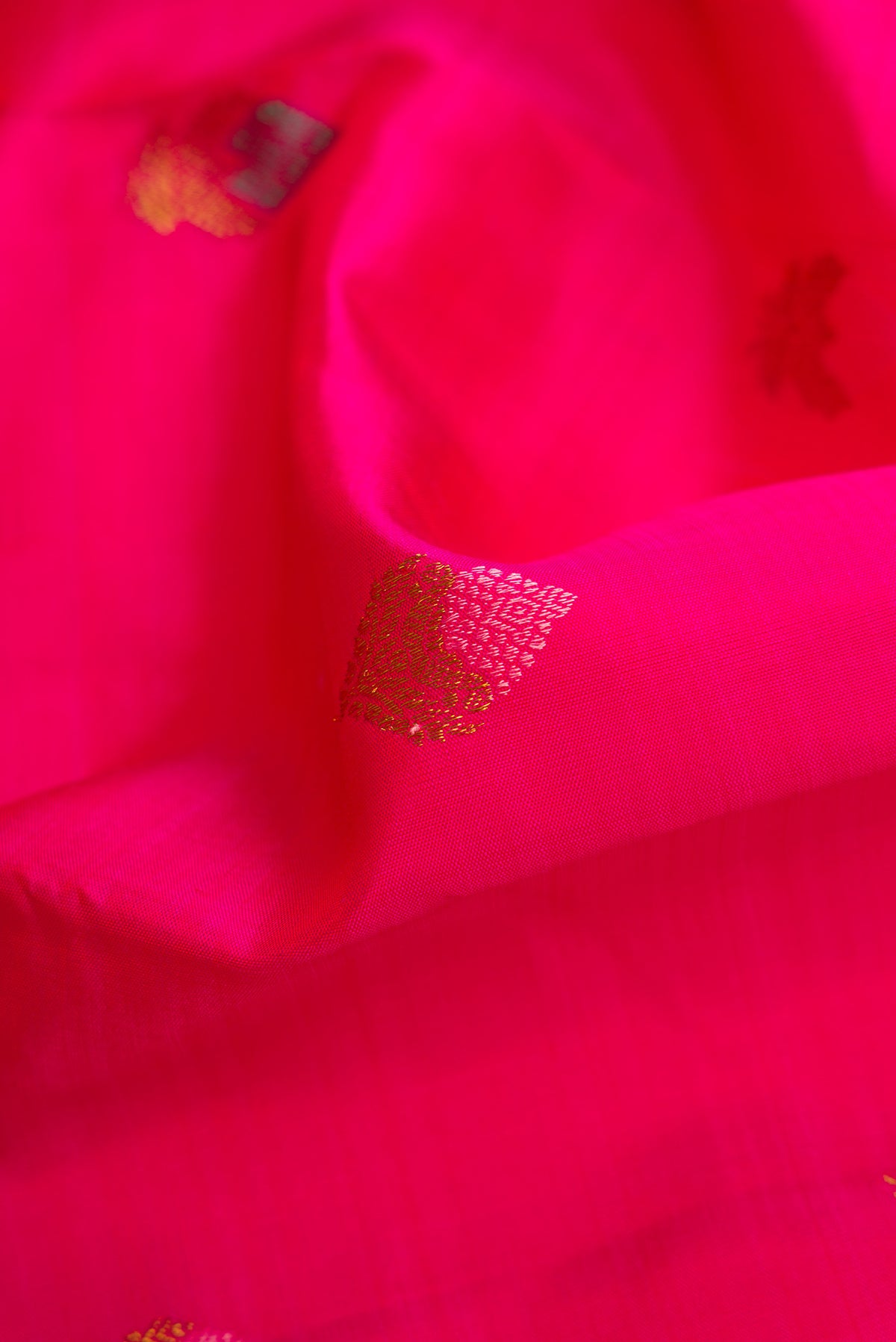 Close up of Pure Silk Pure Zari Pink Kanjivaram Saree with Zari And Thread Butta on the body and Plain Border.  displaying folds