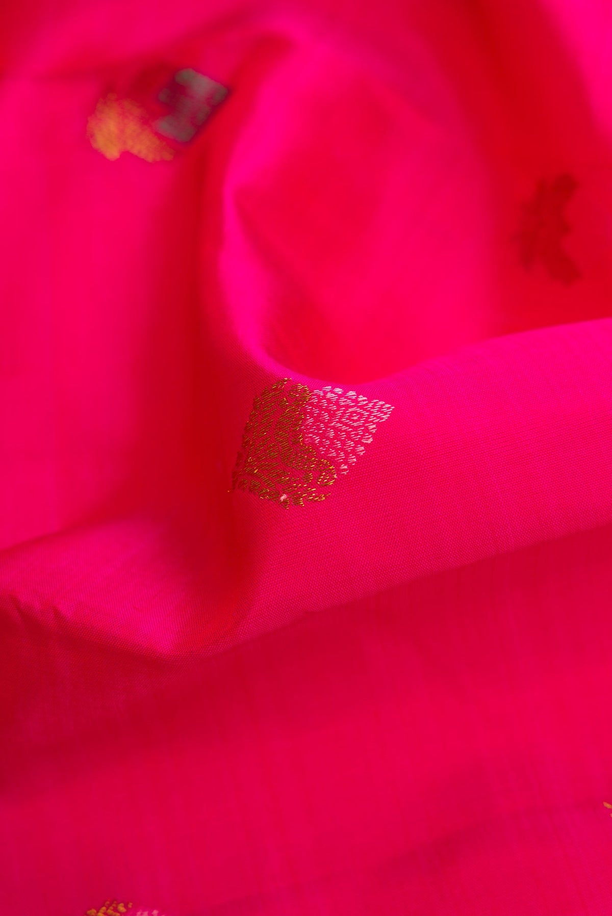 Close up of Pure Silk Pure Zari Pink Dual Tone Kanjivaram Saree with Zari And Thread Butta on the body and Zari Border.  displaying folds
