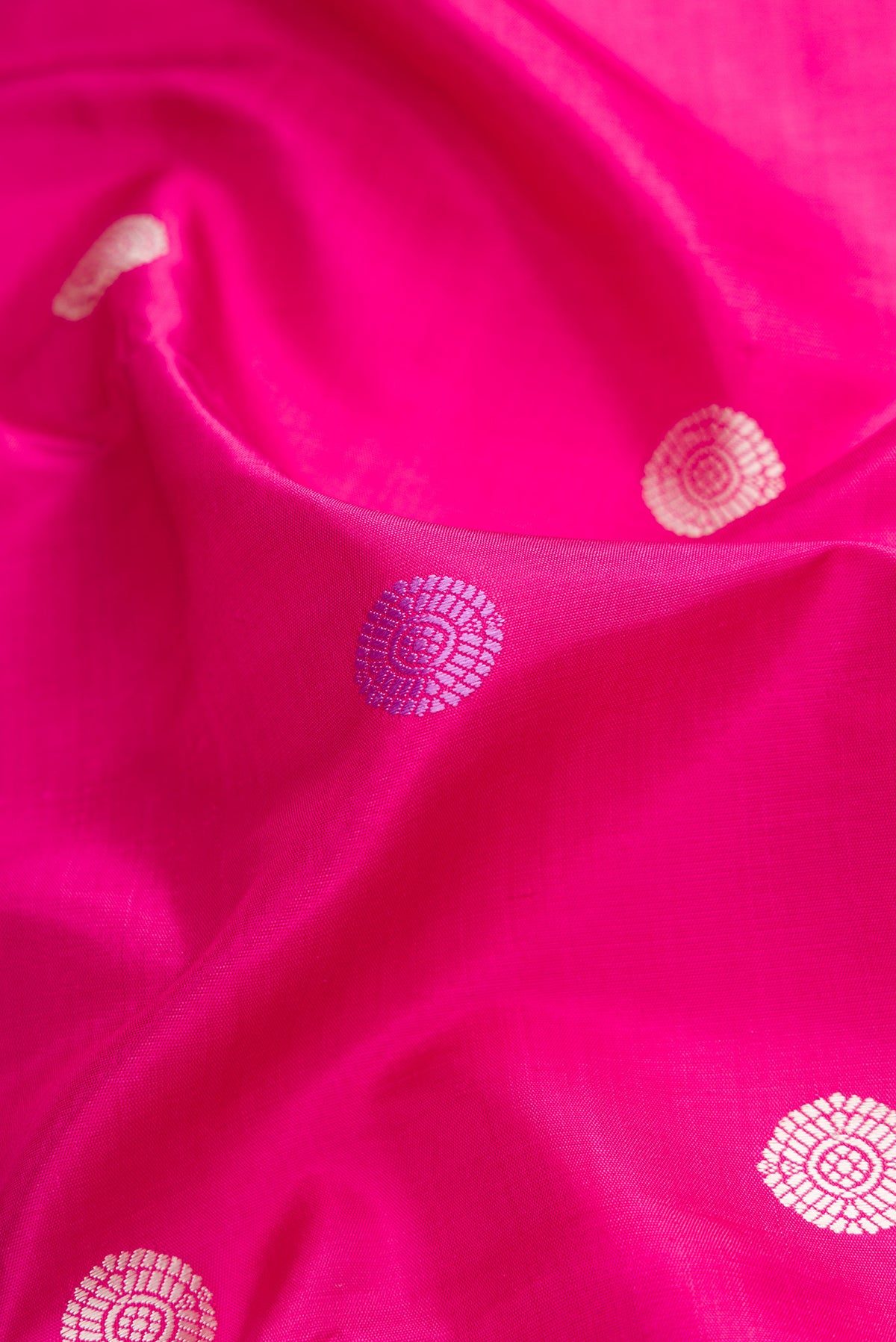 Close up of Pink Kanjivaram Silk Saree with Thread Butta on the body and Zari Border.  displaying folds