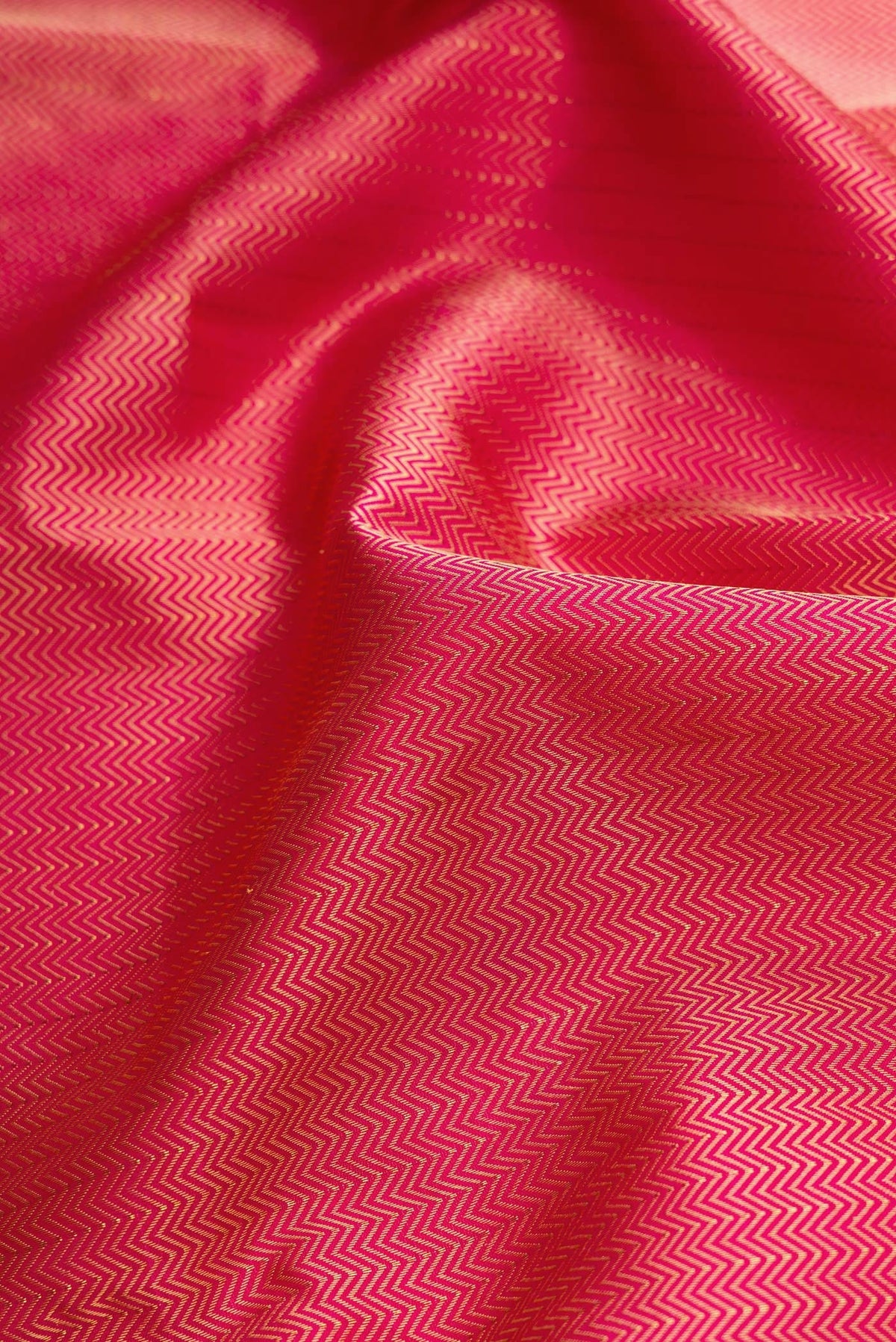 Close up of Dark Pink Dual Tone Kanchipuram Silk Saree with Jacquard design on the body and Zari Border.  displaying folds
