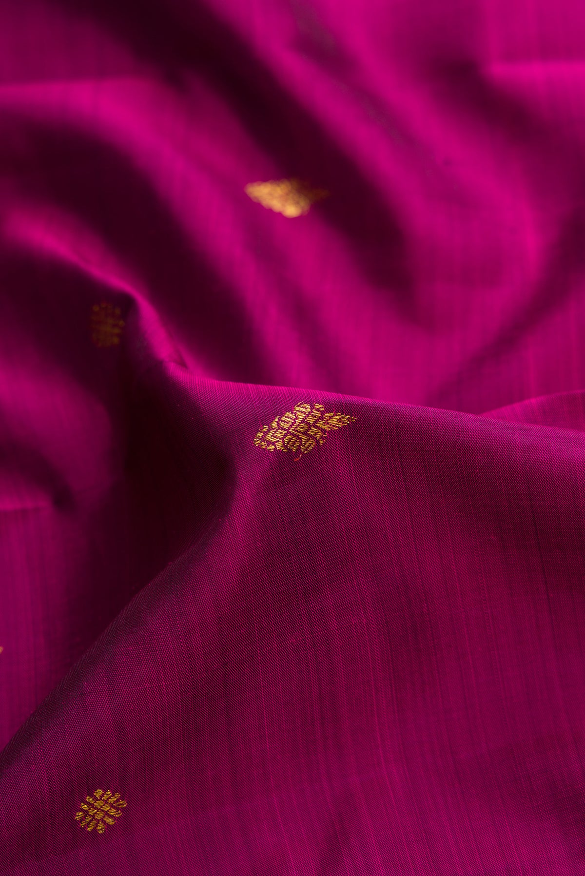 Close up of Magenta Kanjivaram Silk Saree with Zari Butta on the body and Fancy Border.  displaying folds
