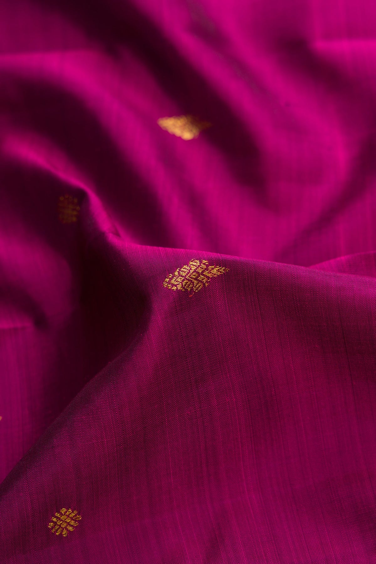 Close up of Magenta Dual Tone Kanjivaram Silk Saree with Zari Butta on the body and Fancy Border.  displaying folds