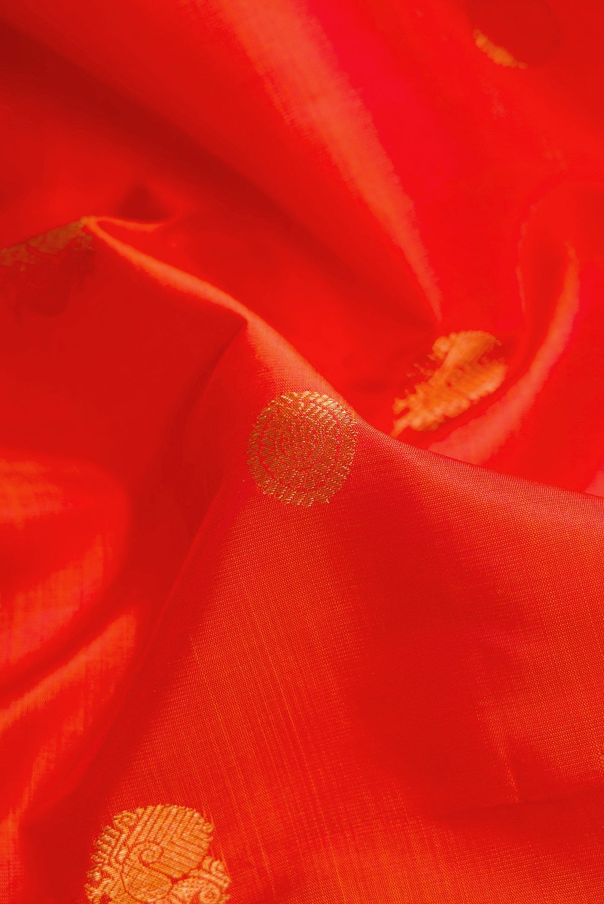 Close up of Orange Dual Tone Kanjivaram Silk Saree with Zari Butta on the body and Zari Border.  displaying folds