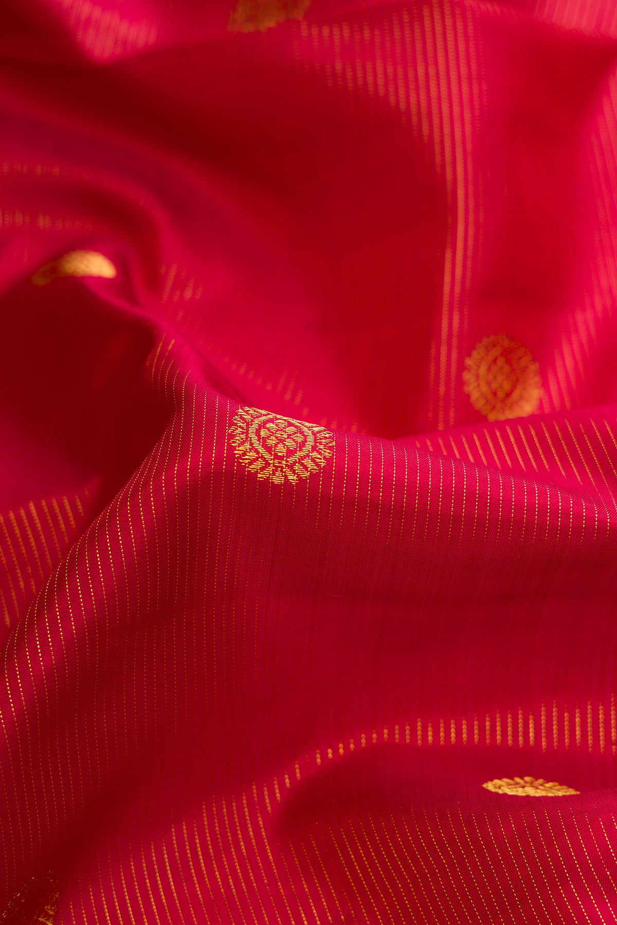 Close up of Red Kanchipuram Silk Saree with Zari Butta on the body and Zari Border.  displaying folds