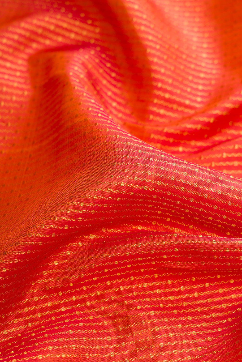Close up of Brick Orange Dual Tone Kanchipuram Silk Saree with Zari Brocade on the body and Zari Border.  displaying folds