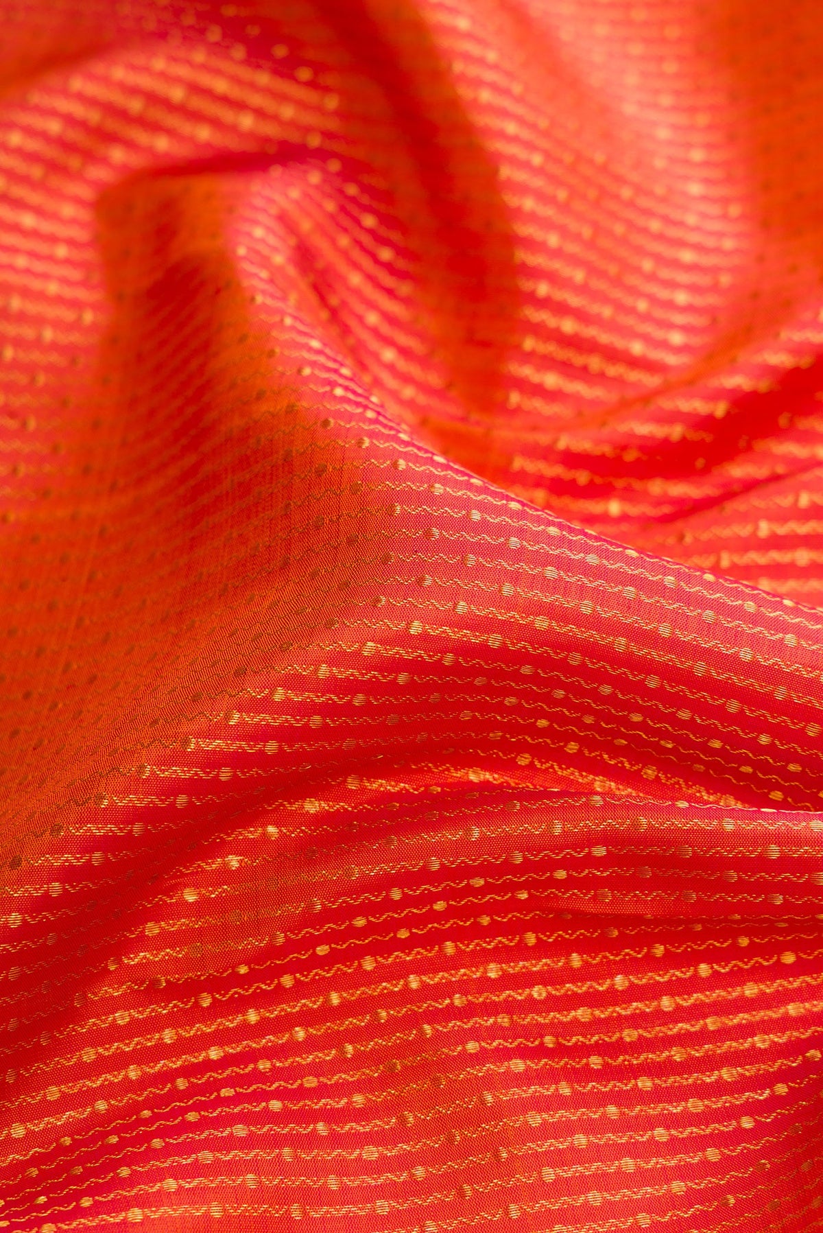 Close up of Brick Orange Dual Tone Kanchipuram Silk Saree with Zari Brocade on the body and Zari Border.  displaying folds