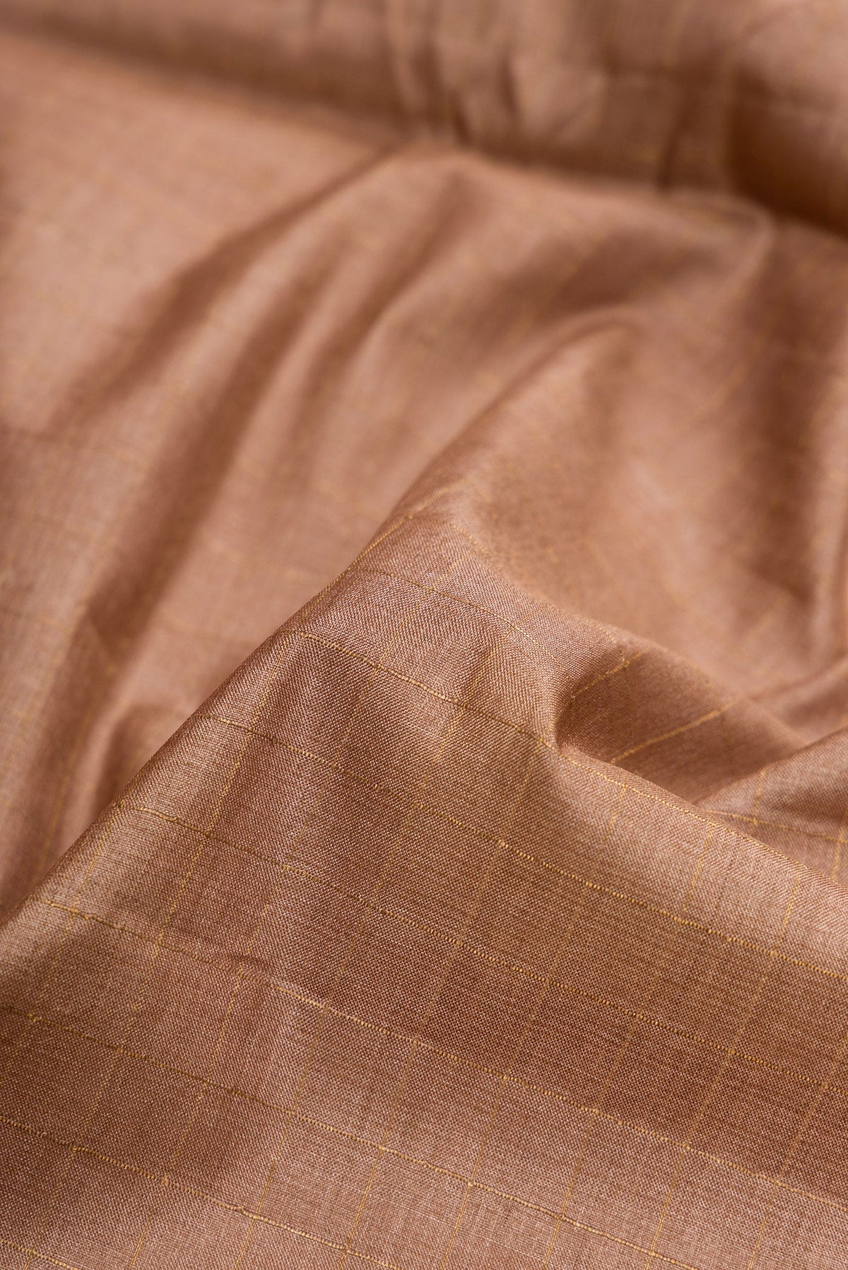 Close up of Brown Dual Tone Tussar Silk Saree with Checked design on the body and Printed Border.  displaying folds
