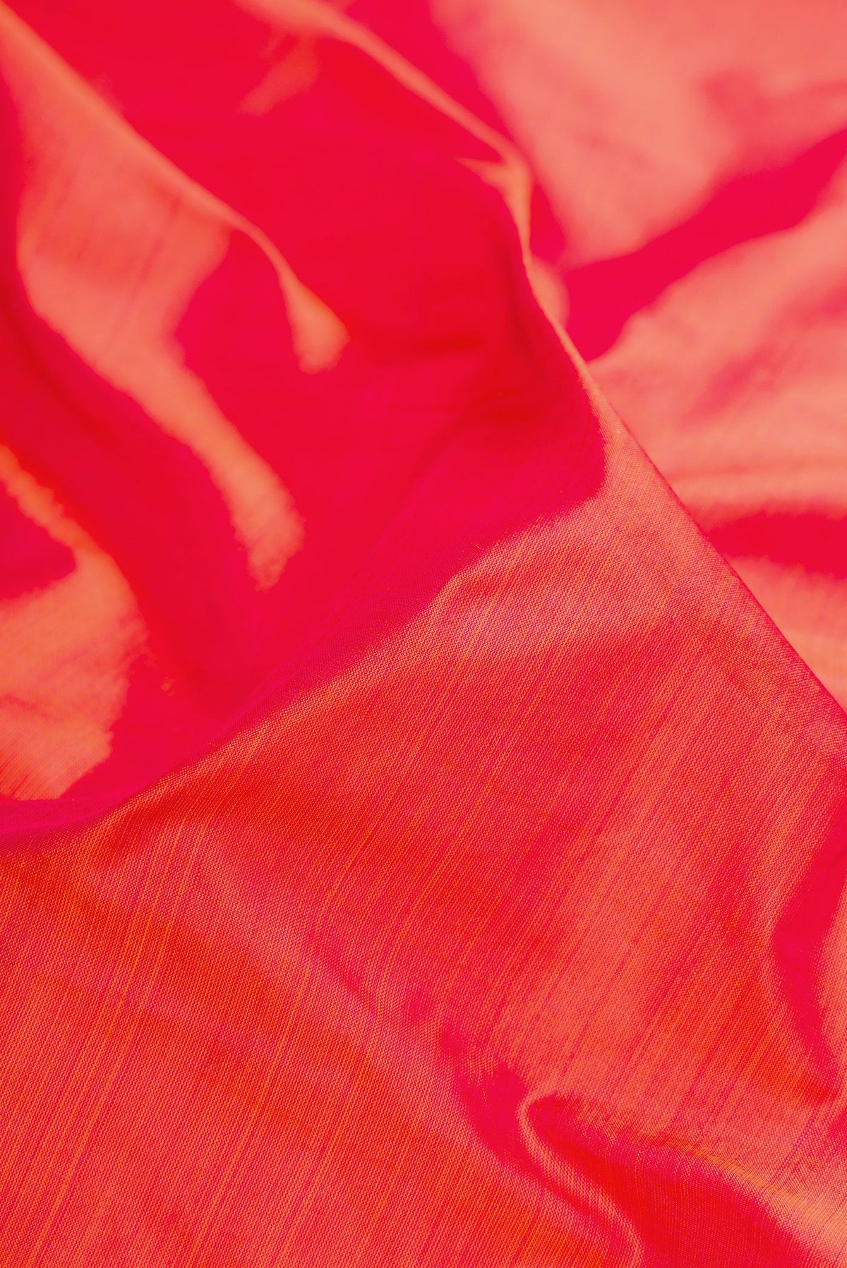 Close up of Coral Dual Tone Kanchipuram Silk Saree with Plain Body and Zari Border.  displaying folds