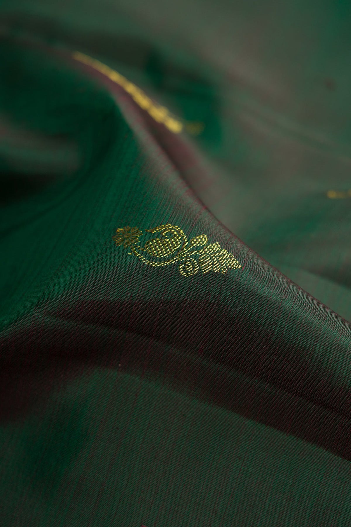 Close up of Bottle Green Dual Tone Kanjivaram Silk Saree with Zari Butta on the body and Zari Border.  displaying folds