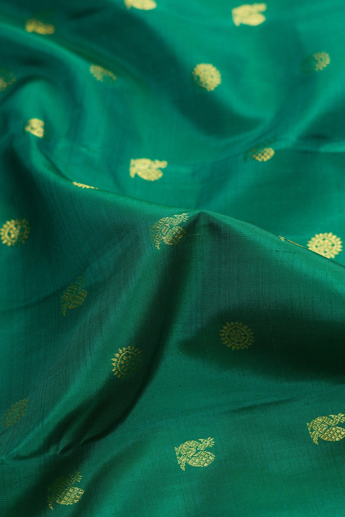 Close up of Green Dual Tone Kanjivaram Silk Saree with Zari Butta on the body and Zari Border.  displaying folds