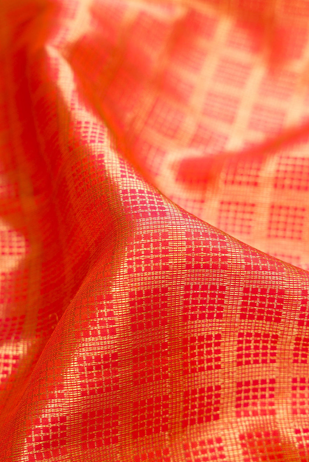 Close up of Orange Dual Tone Kanchipuram Silk Saree with Checked design on the body and Zari Border.  displaying folds