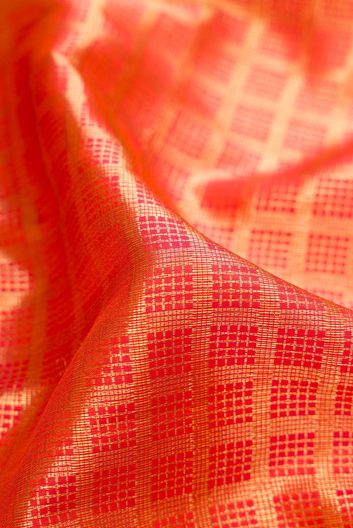 Close up of Orange Dual Tone Kanchipuram Silk Saree with Checked design on the body and Zari Border.  displaying folds