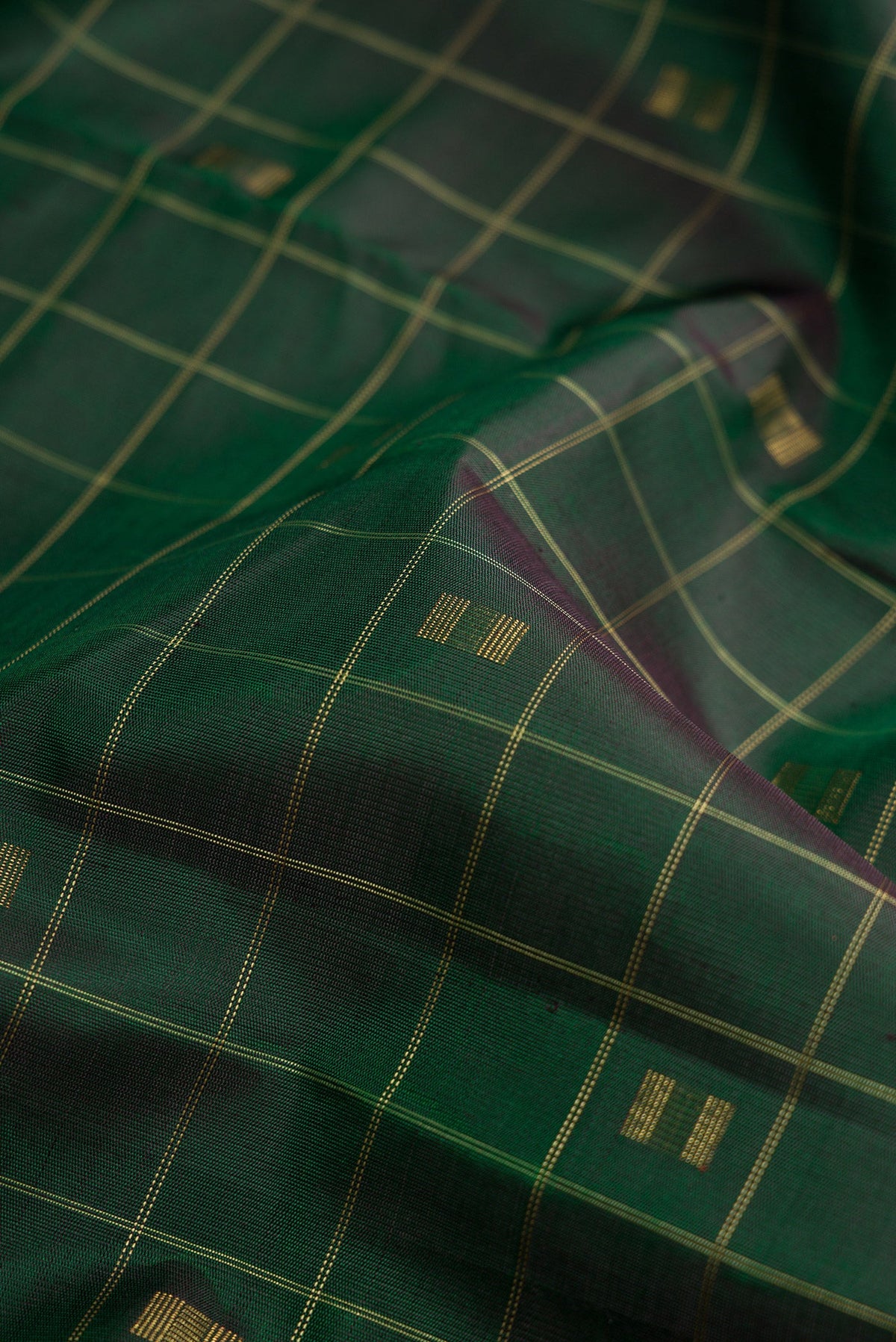 Close up of Pure Silk Pure Zari Green Dual Tone Kanjivaram Saree with Checked design on the body and Without Border.  displaying folds