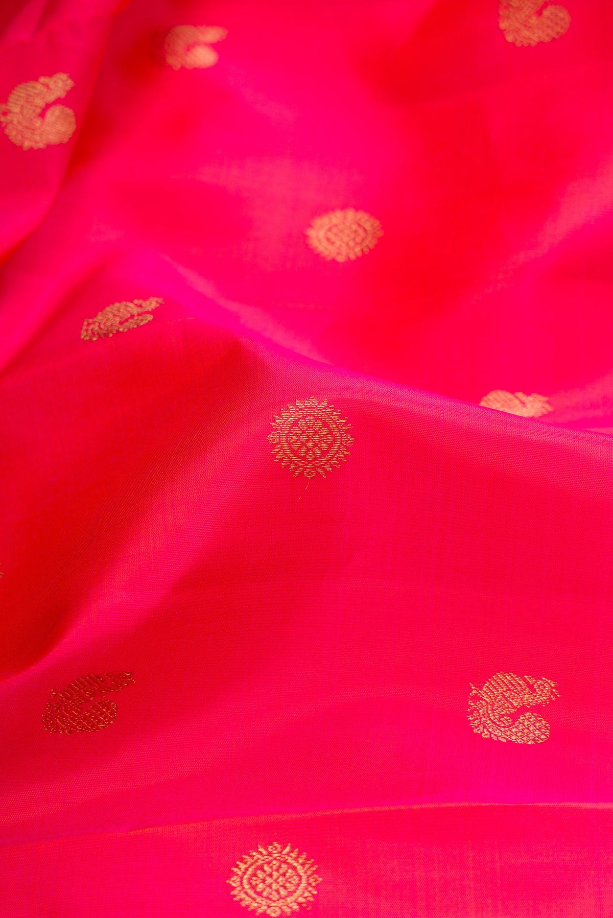 Close up of Pure Silk Pure Zari Coral Dual Tone Kanchipuram Saree with Zari Butta on the body and Fancy Border.  displaying folds