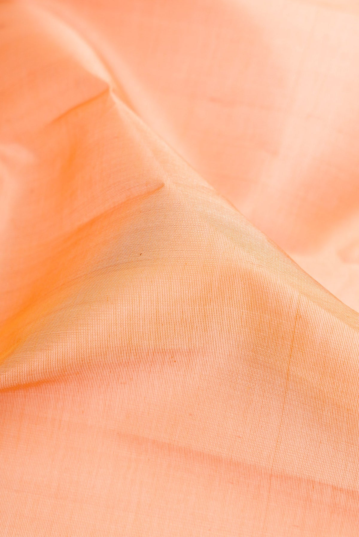 Close up of Peach Silk Cotton Saree with Plain Body and Zari Border.  displaying folds