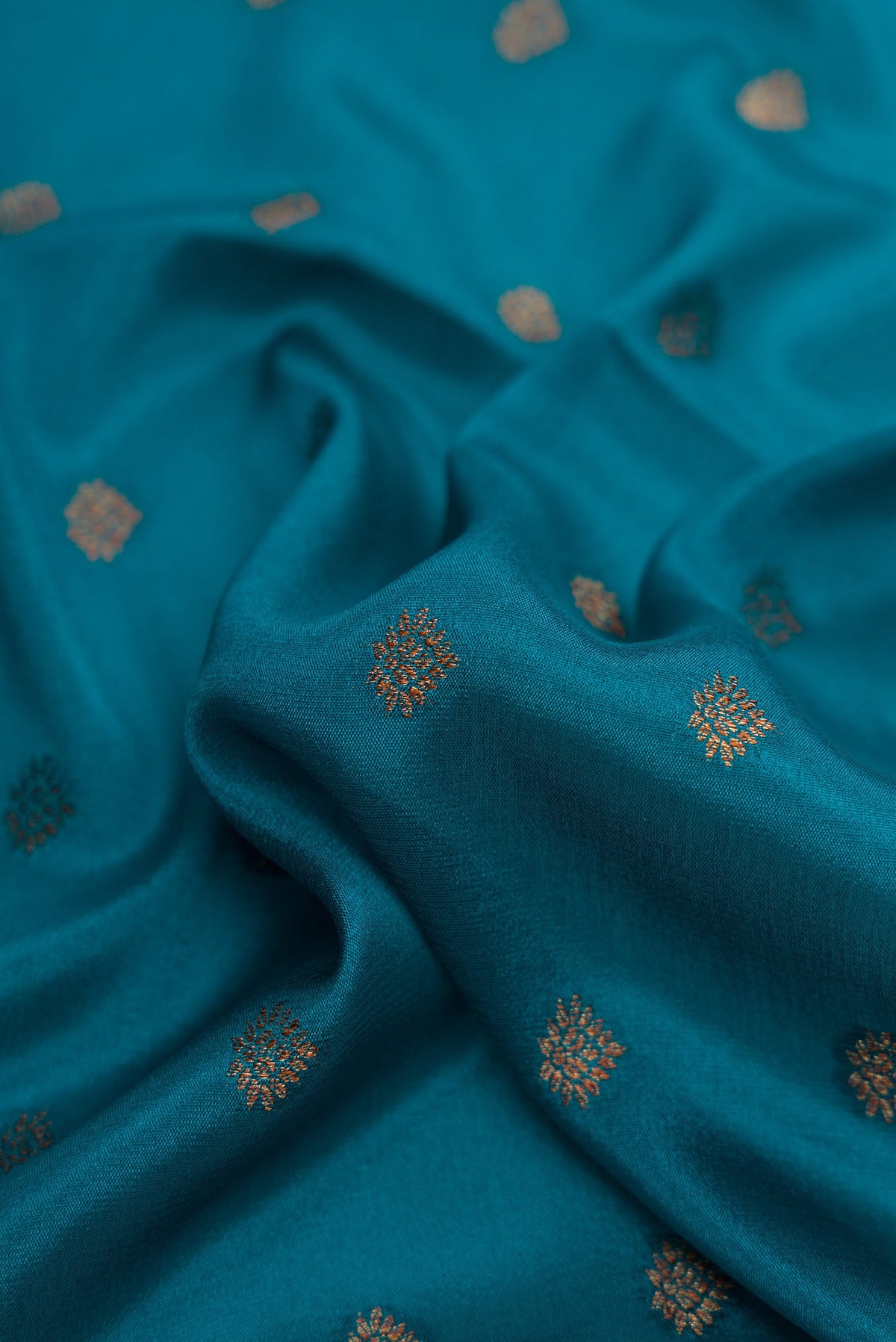 Close up of Peacock Blue Dual Tone Mysore Crepe Saree with Zari Butta on the body and Fancy Border.  displaying folds