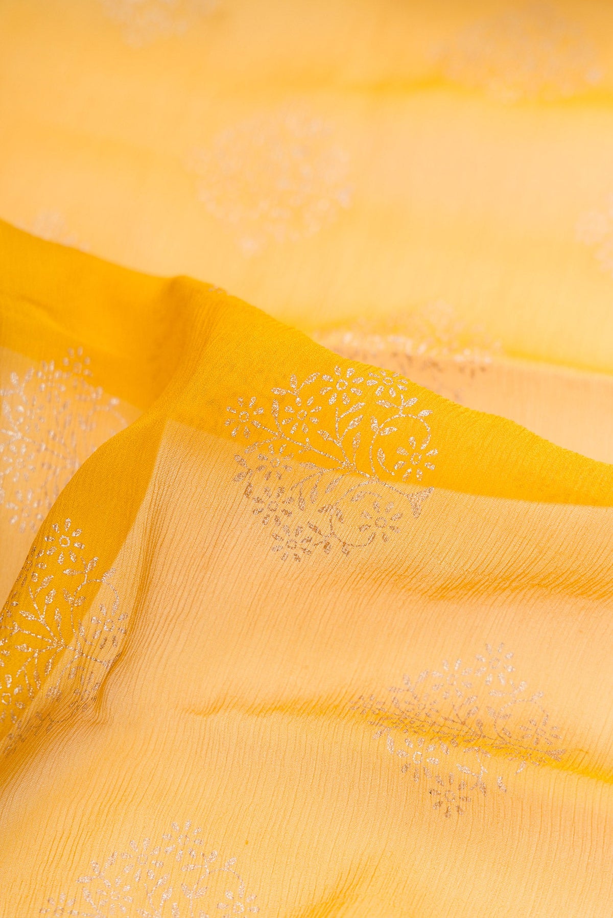 Close up of Yellow Dual Tone Mysore Chiffon Saree with Printed design on the body and Zari Border.  displaying folds