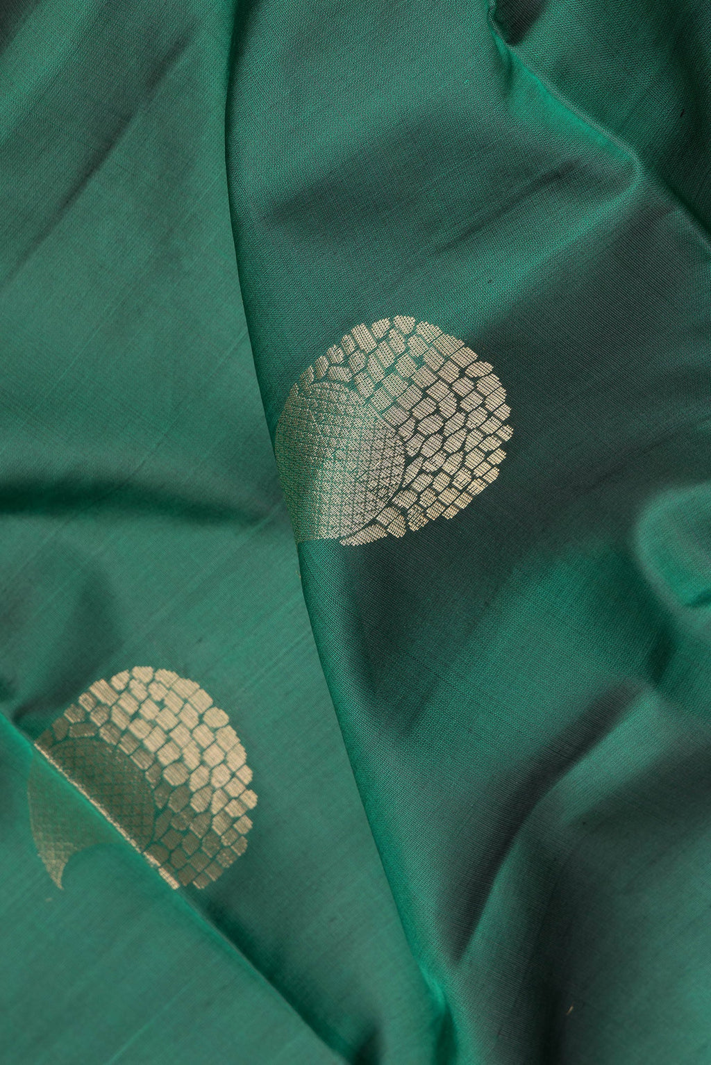 Close up of Green Soft Silk Saree with Zari Butta on the body and Zari Border.  displaying folds