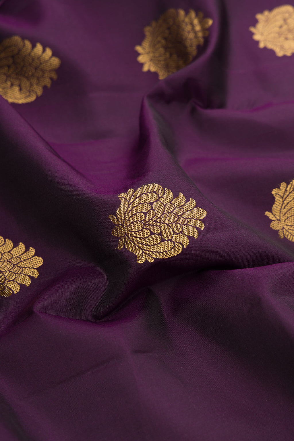 Close up of Burgundy Dual Tone Kanchipuram Silk Saree with Zari Butta on the body and Zari Border.  displaying folds