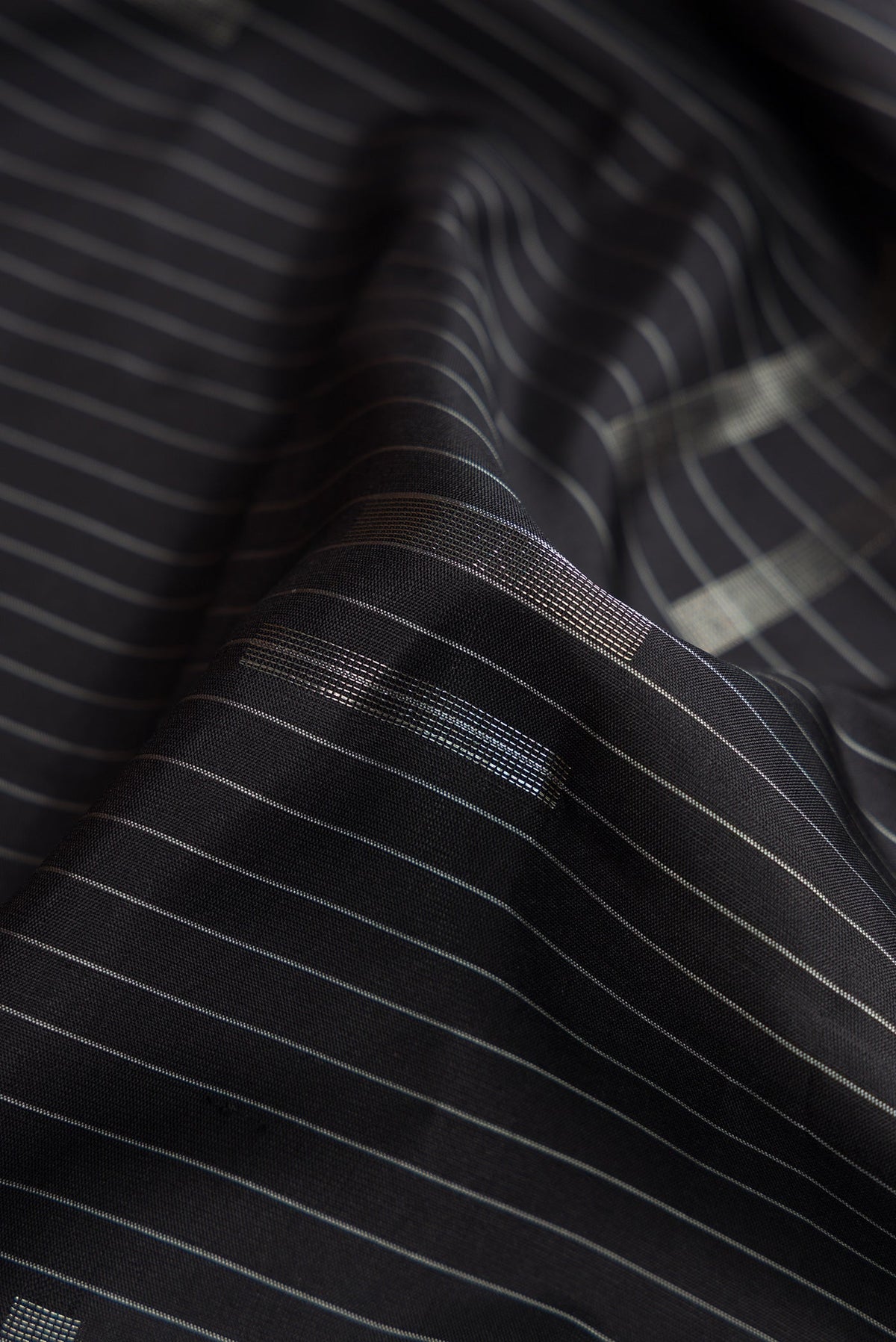 Close up of Black Dual Tone Soft Silk Saree with Stripes on the body and Zari Border.  displaying folds