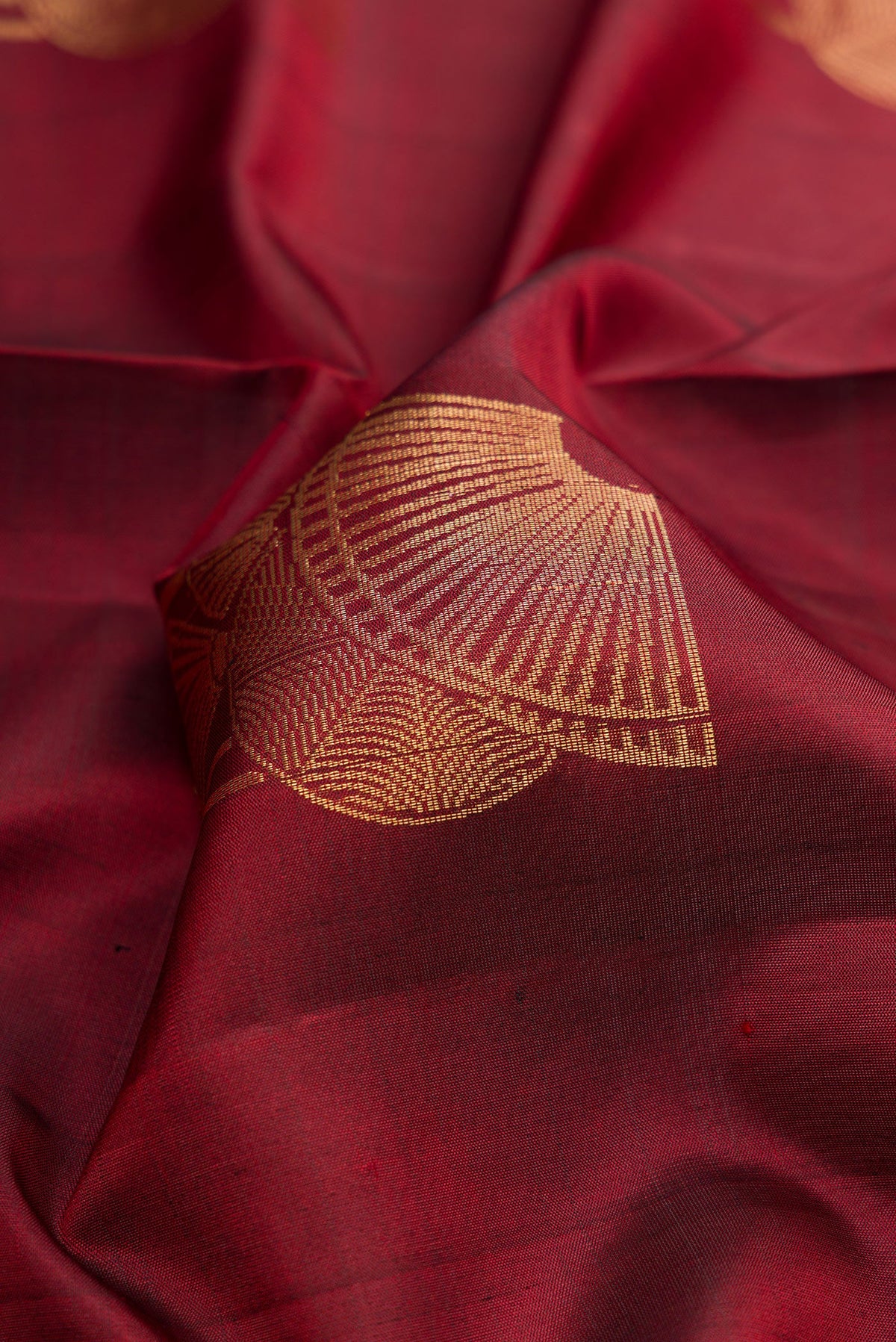 Close up of Maroon Dual Tone Soft Silk Saree with Zari Butta on the body and Zari Border.  displaying folds