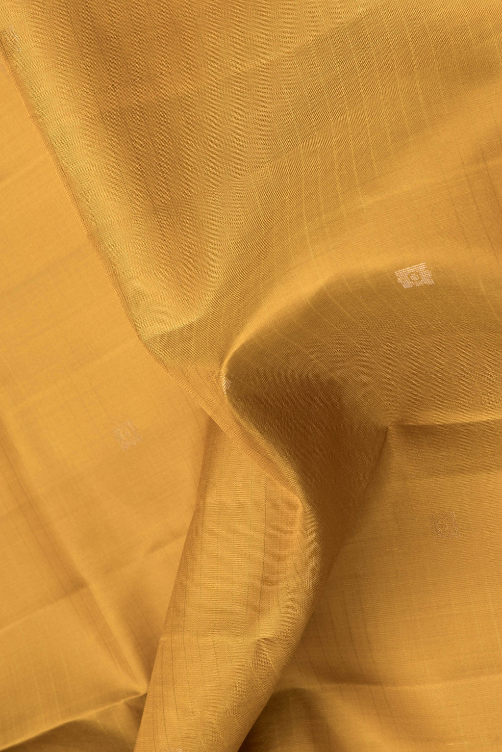 Close up of Mustard Dual Tone Soft Silk Saree with Zari Butta on the body and Zari Border.  displaying folds