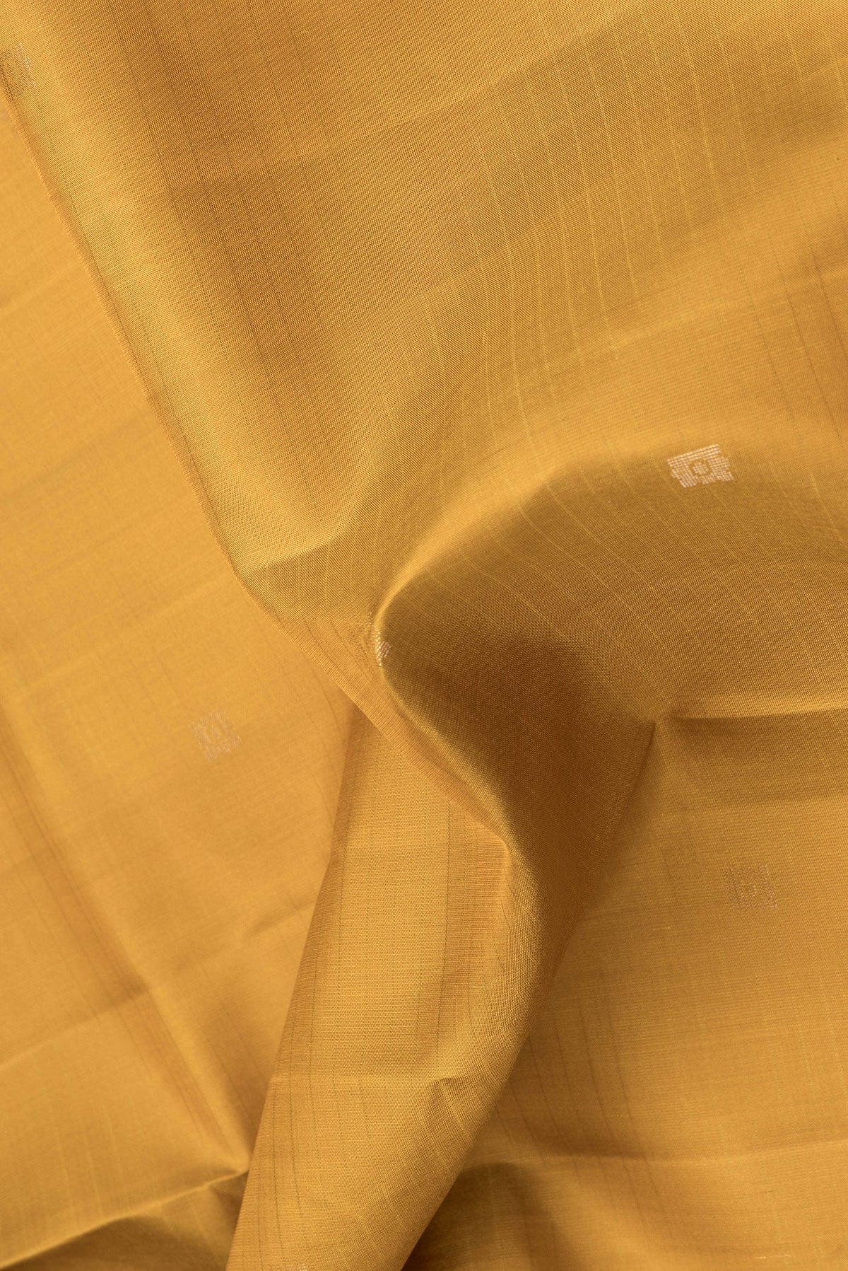 Close up of Mustard Dual Tone Soft Silk Saree with Zari Butta on the body and Zari Border.  displaying folds
