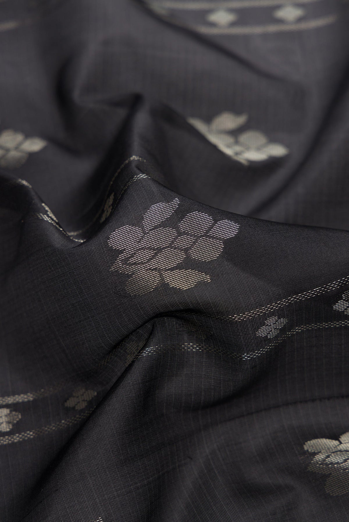 Close up of Black Dual Tone Soft Silk Saree with Zari Butta on the body and Zari Border.  displaying folds