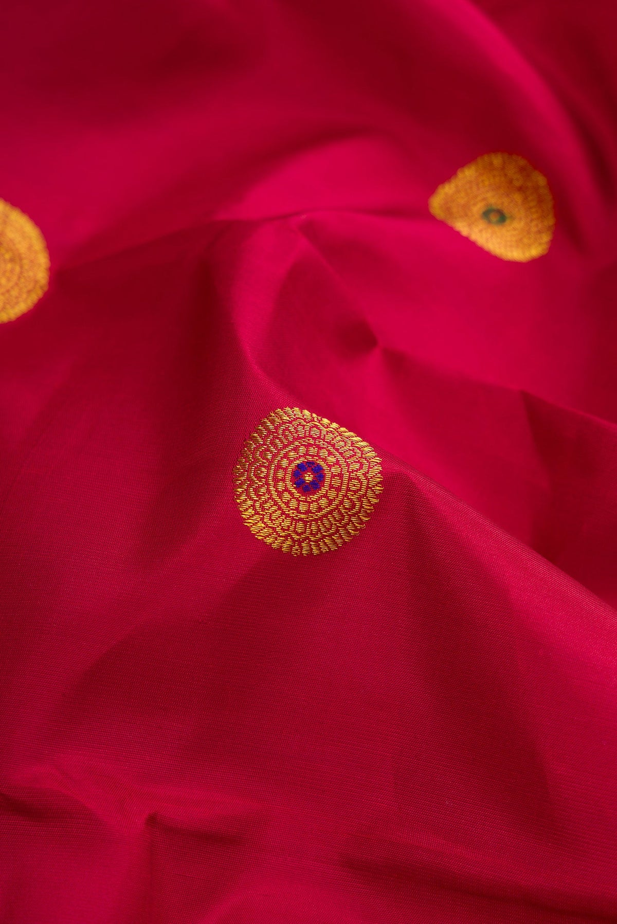 Close up of Maroon Kanchipuram Silk Saree with Zari And Thread Butta on the body and Thin Zari Line.  displaying folds