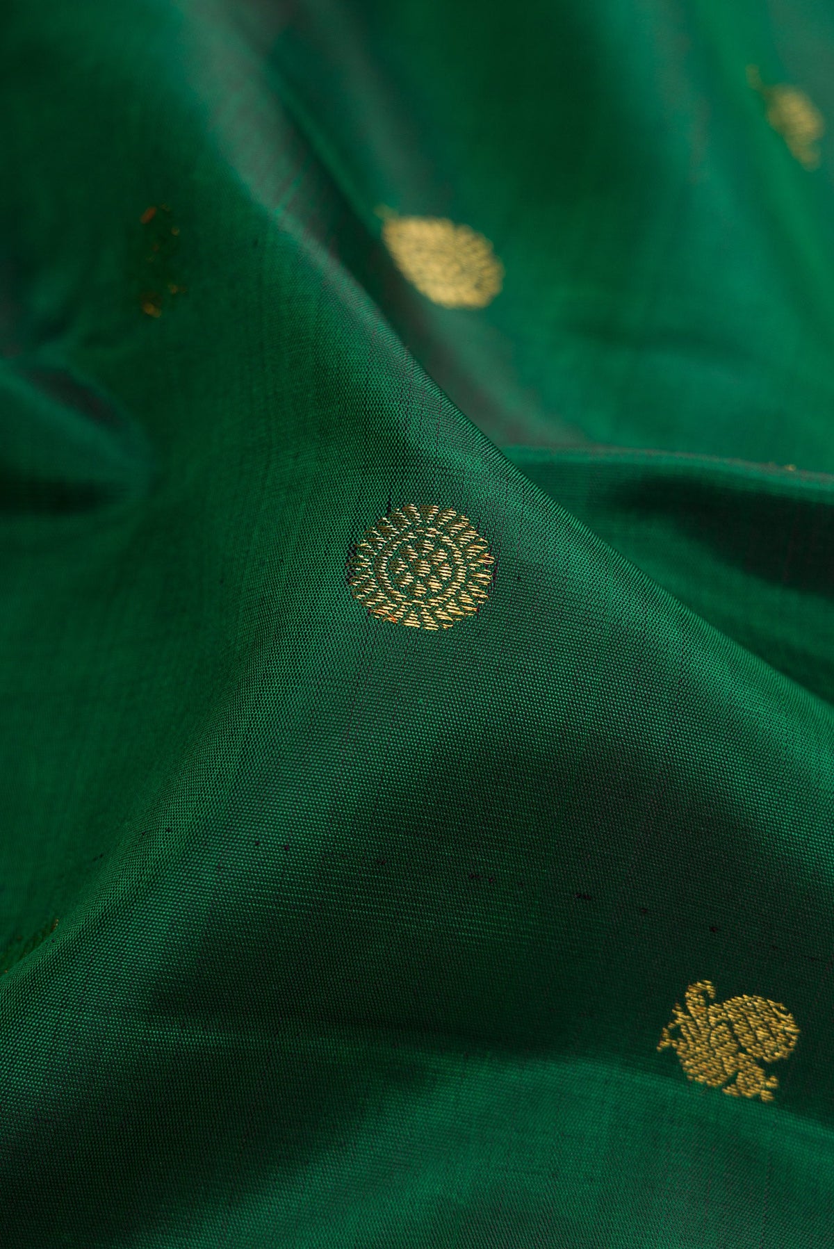 Close up of Pure Silk Pure Zari Green Dual Tone Kanjivaram Saree with Zari Butta on the body and Zari Border.  displaying folds