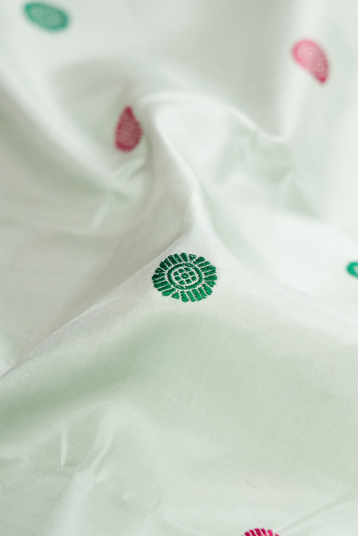 Close up of Pista Green Kanchipuram Silk Saree with Thread Butta on the body and Zari Border.  displaying folds