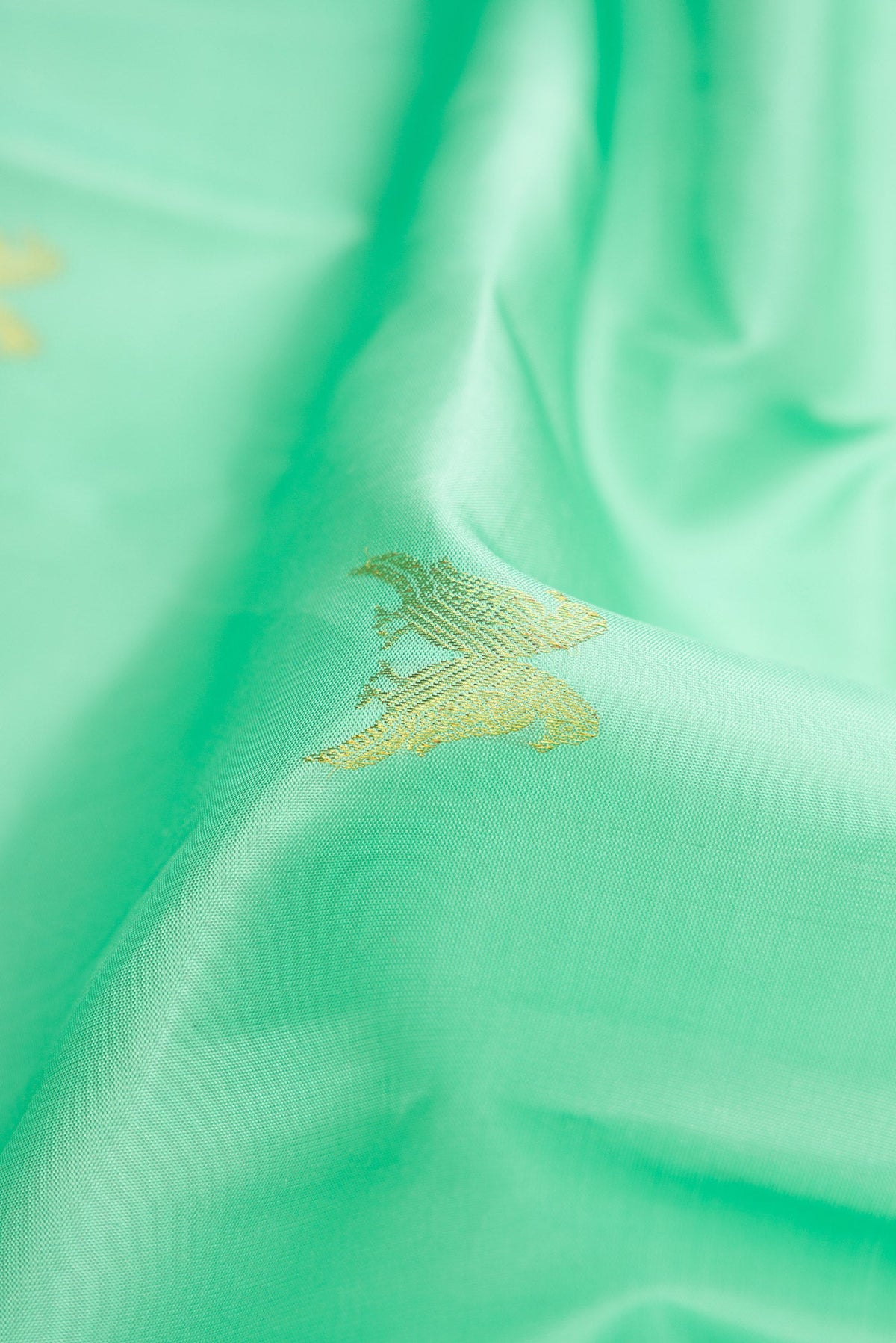 Close up of Sea Green Dual Tone Kanchipuram Silk Saree with Zari Butta on the body and Thin Zari Line.  displaying folds