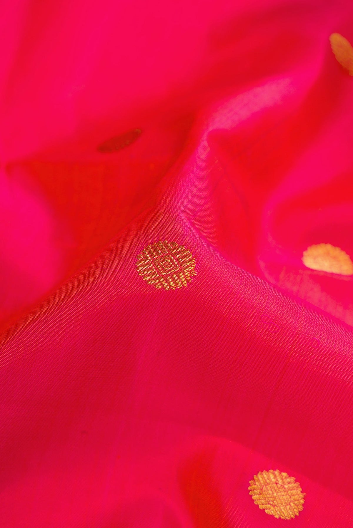 Close up of Coral Dual Tone Kanchipuram Silk Saree with Zari Butta on the body and Zari Border.  displaying folds