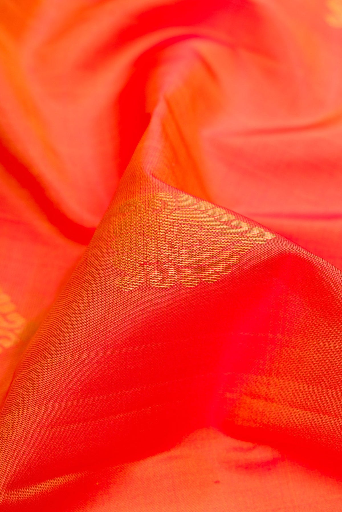 Close up of Orange Dual Tone Soft Silk Saree with Zari Butta on the body and Fancy Border.  displaying folds