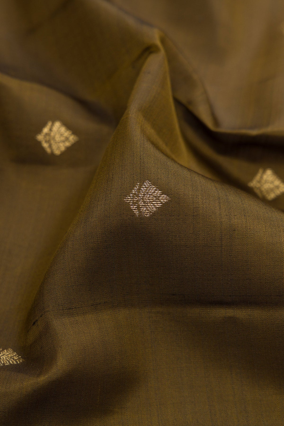 Close up of Mehandi Green Kanchipuram Silk Saree with Zari Butta on the body and Zari Border.  displaying folds