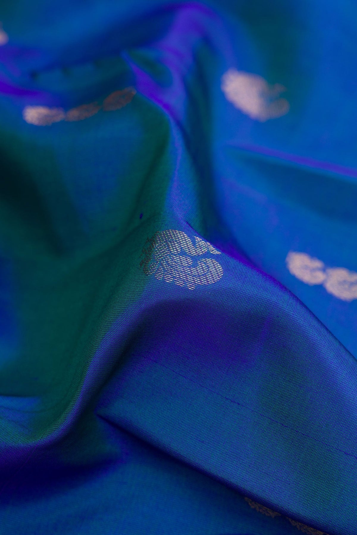 Close up of Peacock Blue Dual Tone Kanchipuram Silk Saree with Zari Butta on the body and Zari Border.  displaying folds