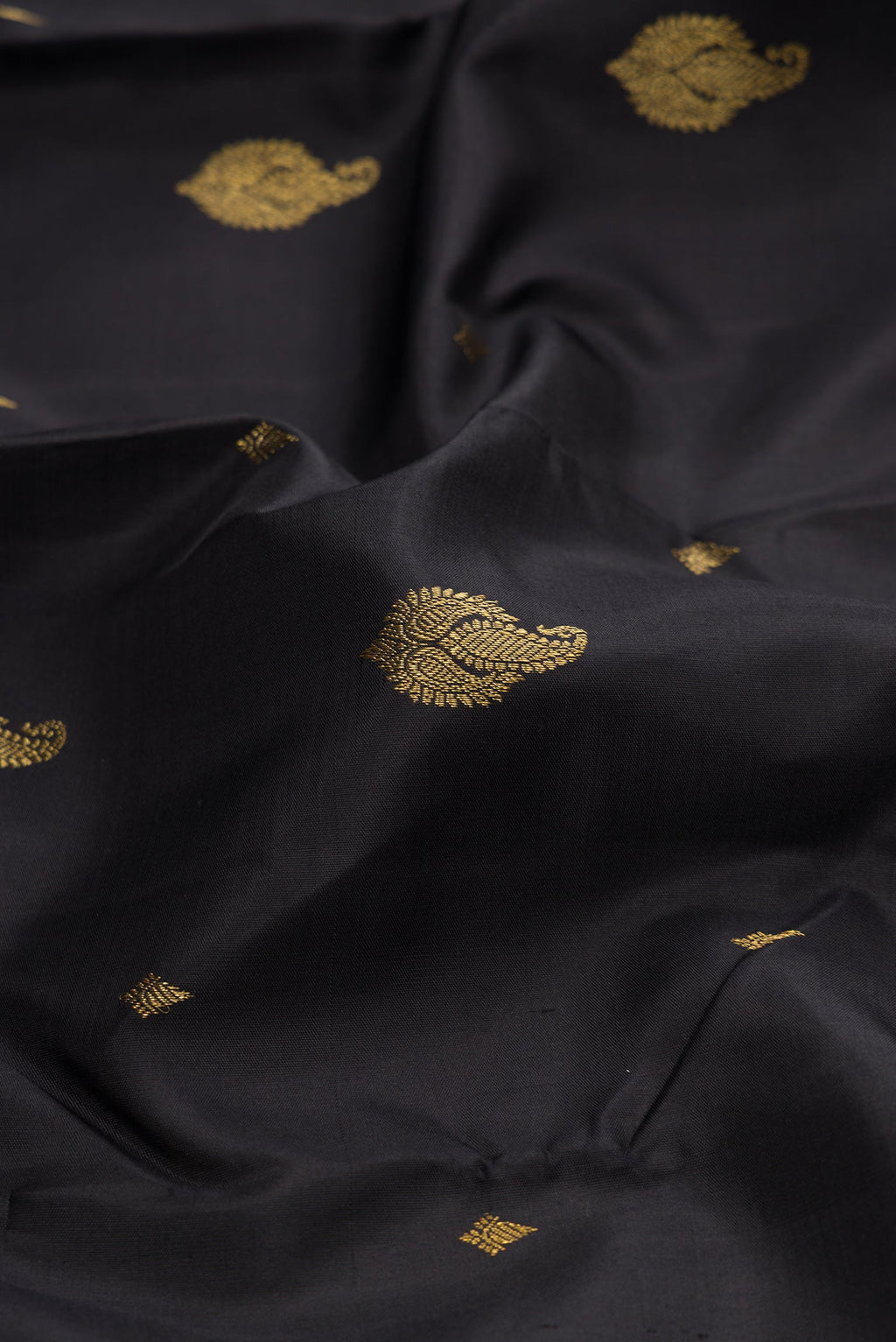 Close up of Black Kanchipuram Silk Saree with Zari Butta on the body and Zari Border.  displaying folds