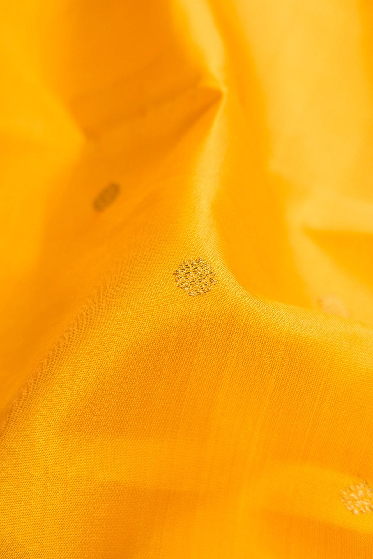 Close up of Pure Silk Pure Zari Yellow Dual Tone Kanjivaram Saree with Zari Butta on the body and Zari Border.  displaying folds