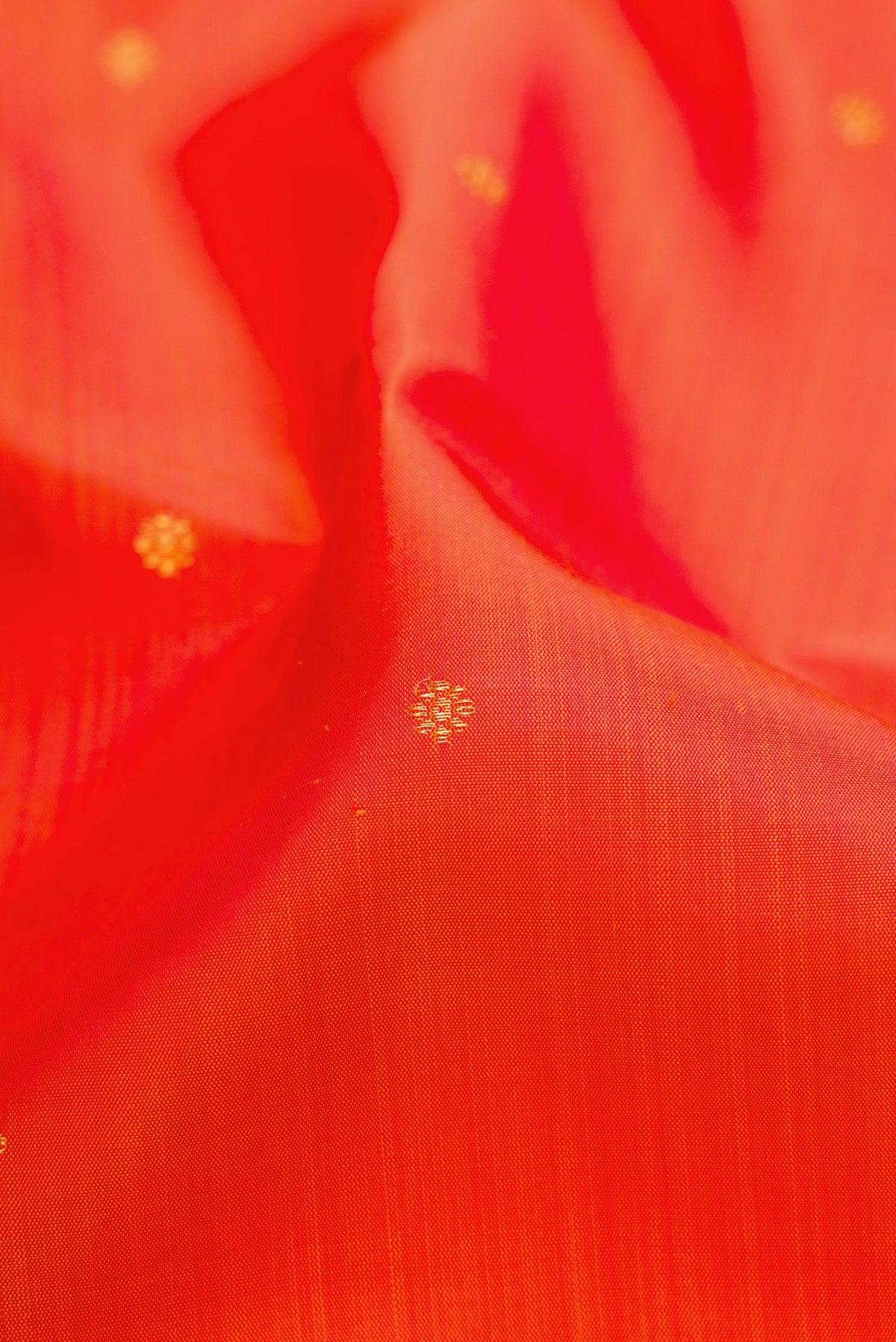 Close up of Orange Dual Tone Kanchipuram Silk Saree with Zari Butta on the body and Zari Border.  displaying folds