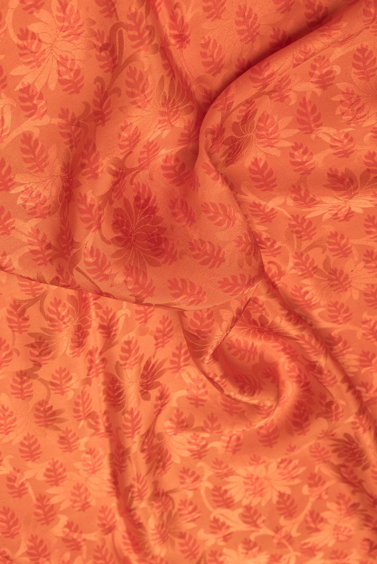 Close up of Orange Dual Tone Mysore Crepe Saree with Printed design on the body and Printed Border.  displaying folds