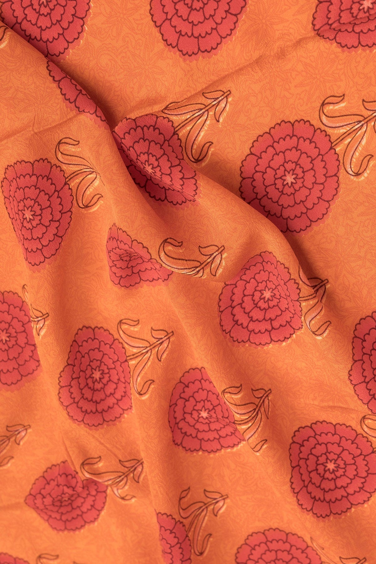 Close up of Orange Dual Tone Mysore Crepe Saree with Printed design on the body and Printed Border.  displaying folds
