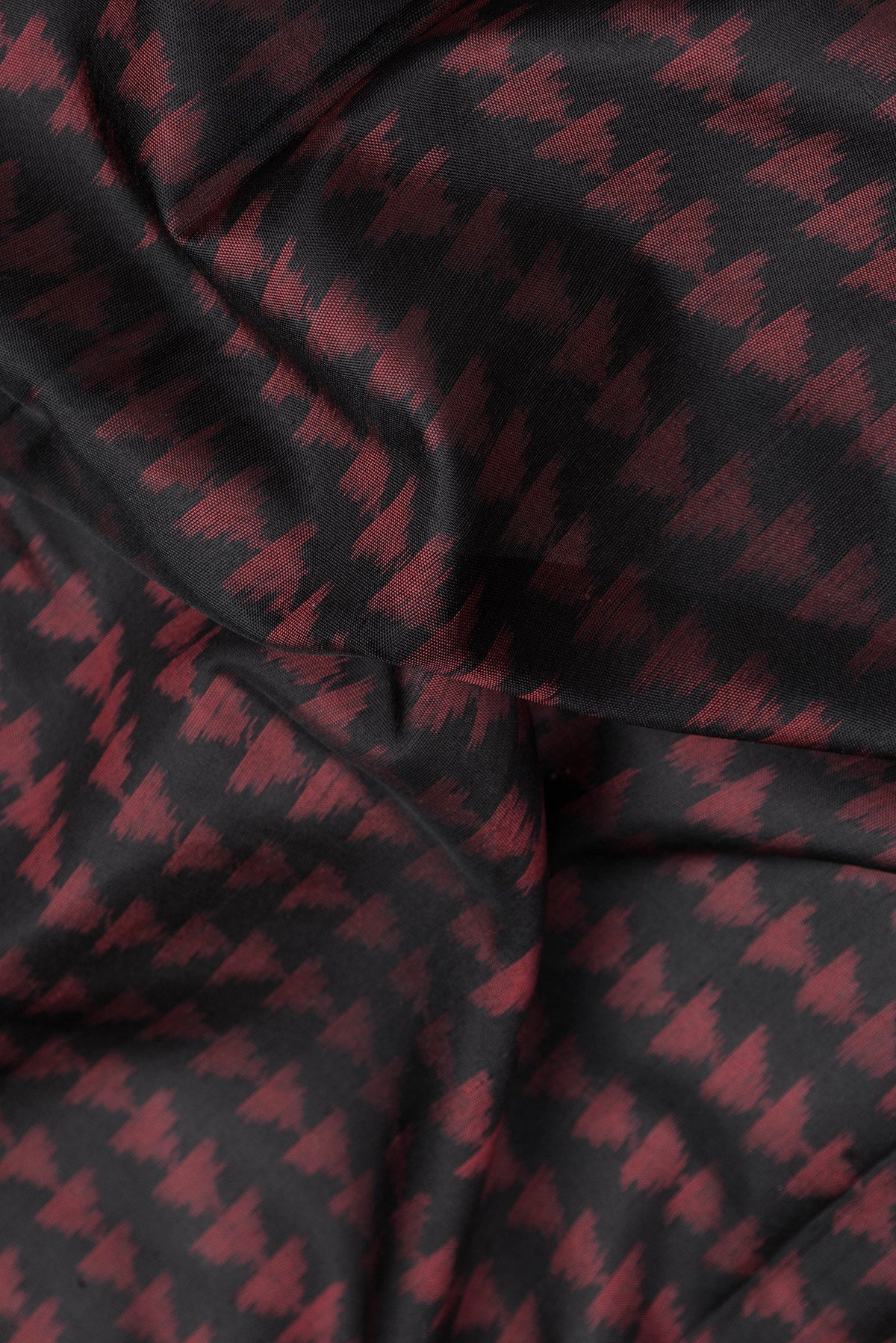 Close up of Black Dual Tone Double Ikat Saree with Ikat Print on the body and Fancy Border.  displaying folds