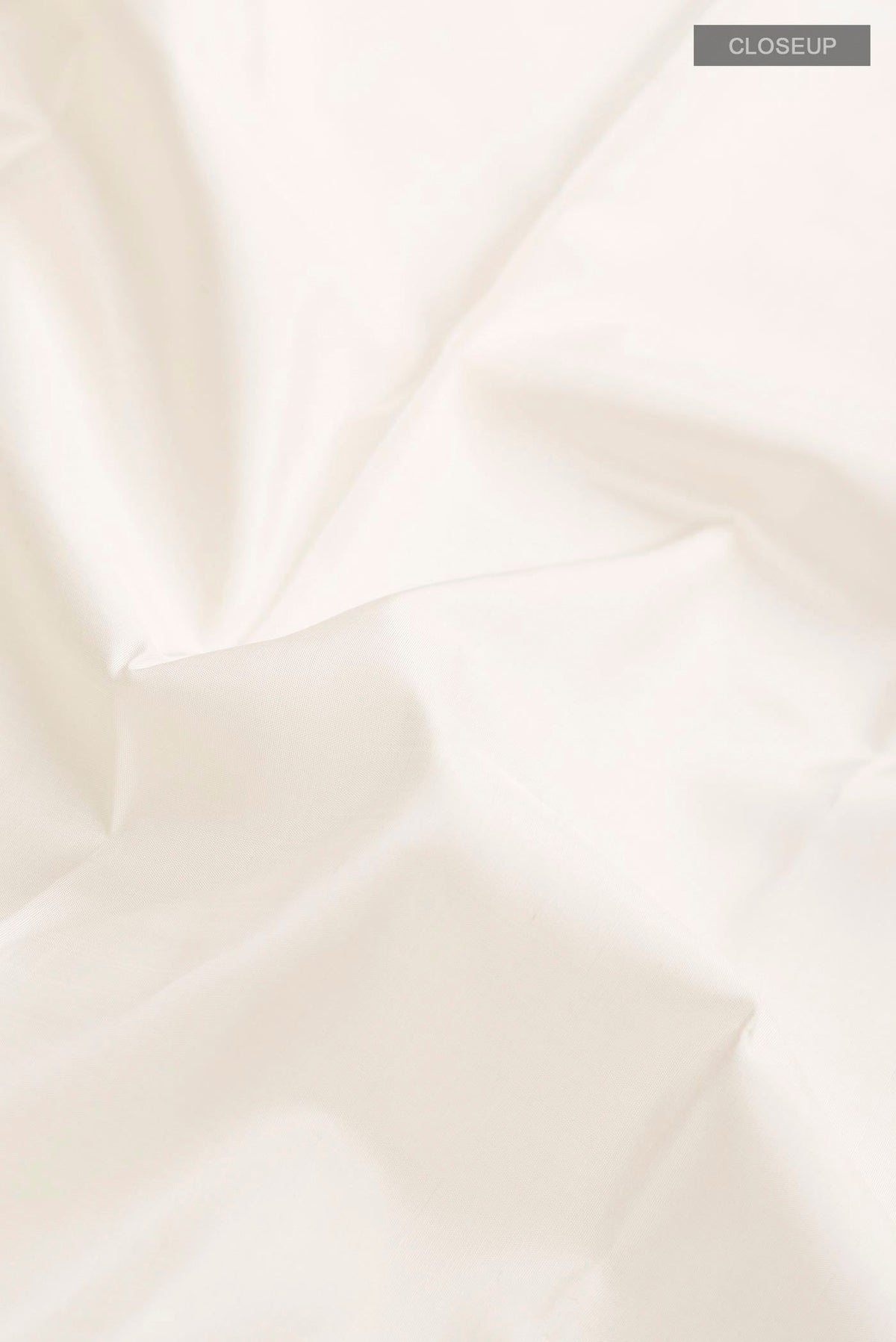 Close up of White Kanchipuram Silk Saree with Plain Body and Zari Border displaying folds