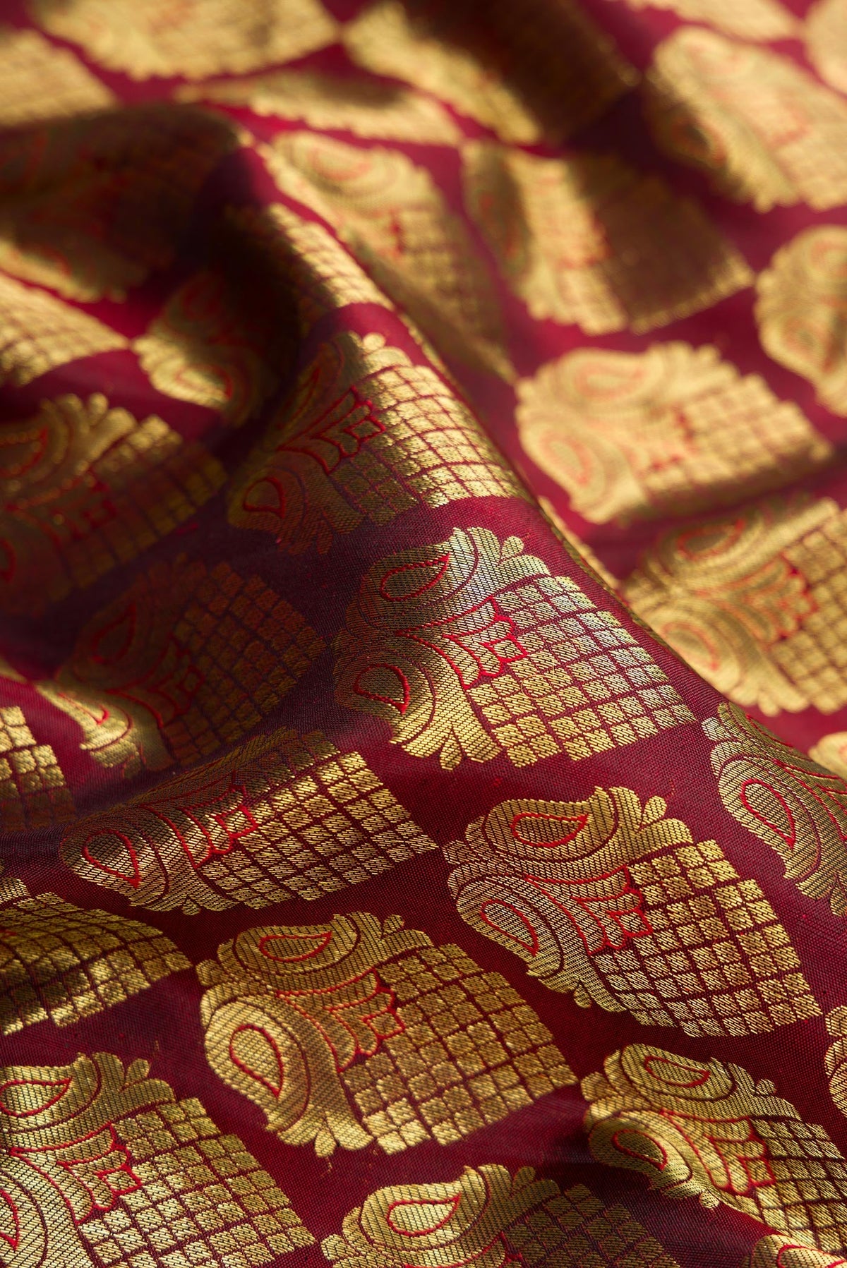 Close up of Maroon Dual Tone Kanjivaram Silk Saree with Zari Brocade on the body and Zari Border.  displaying folds