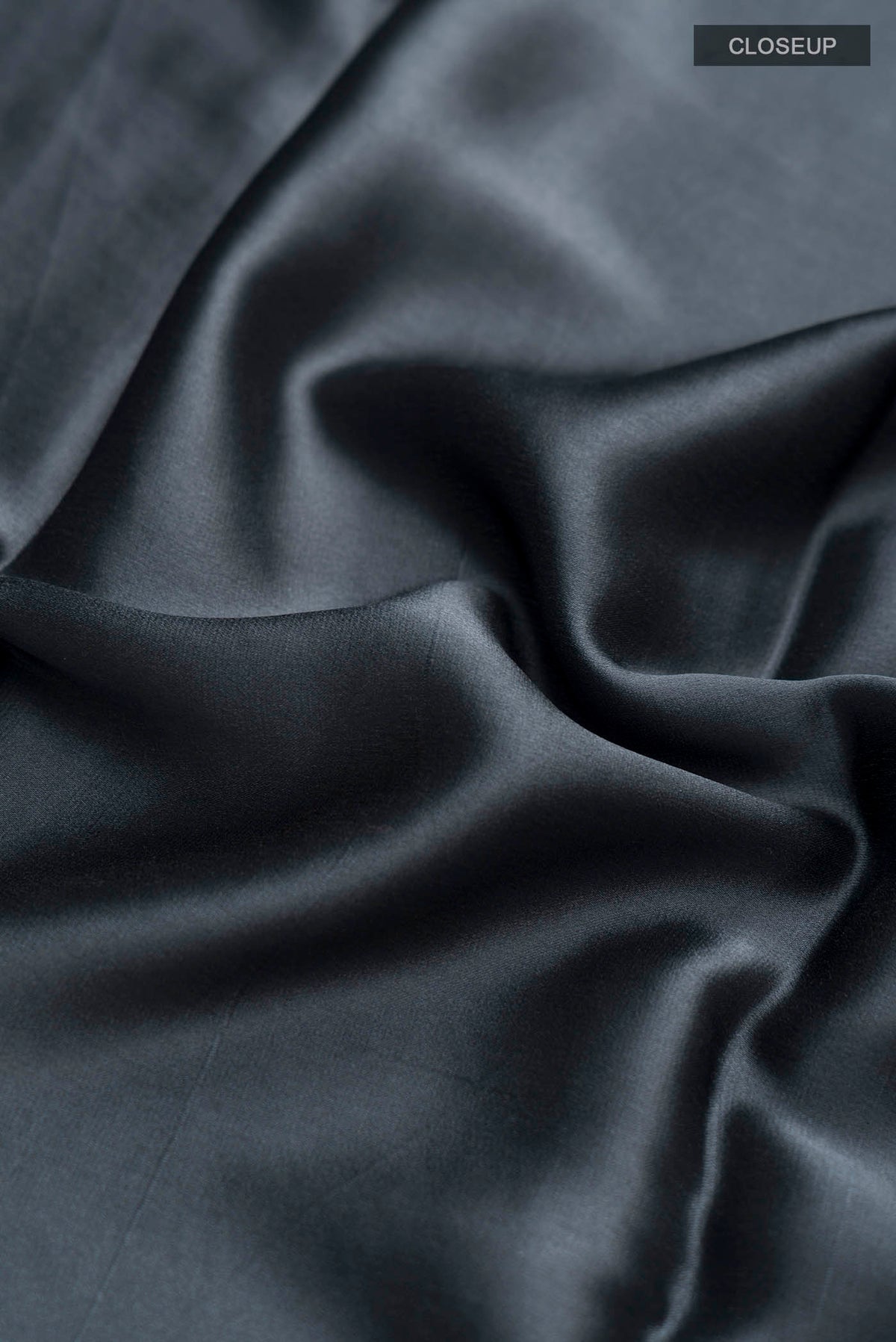Close up of Grey Satin Silk Saree with Plain Body and Zari Border displaying folds