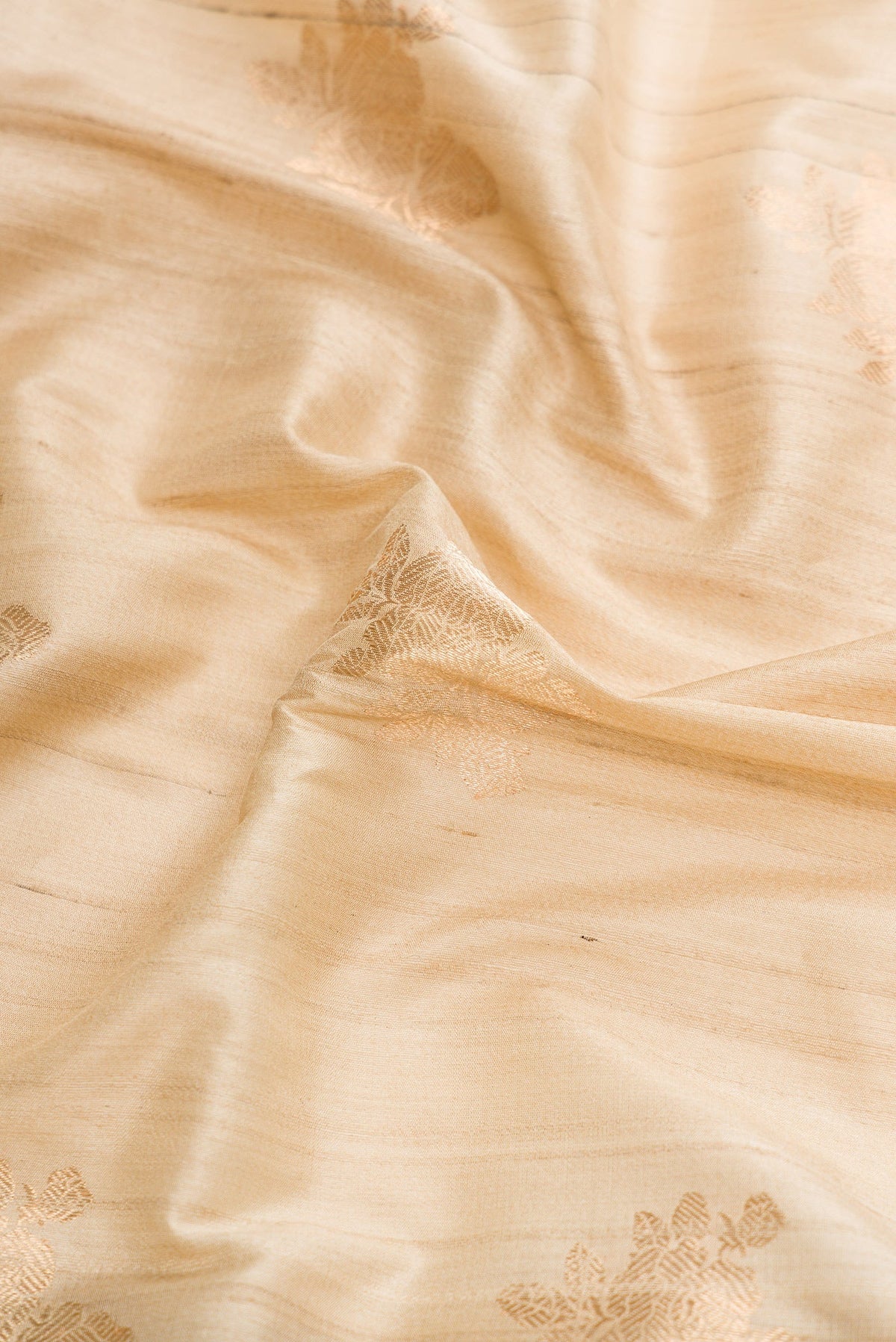 Close up of Beige Dual Tone Tussar Silk Saree with Zari Butta on the body and Zari And Thread Border.  displaying folds