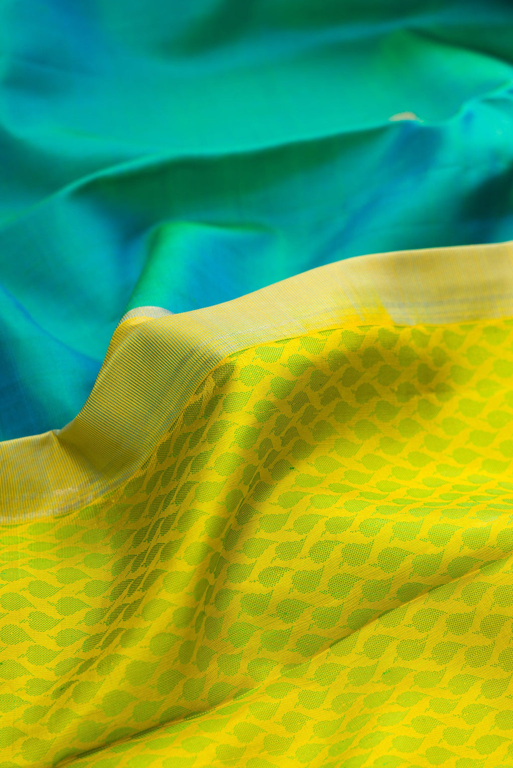 Close up of Yellow Dual Tone Kanjivaram Silk Saree with Half And Half on the body and Without Border.  displaying folds